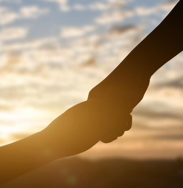 two hands holding at sunset in a warm glow harmony and connection