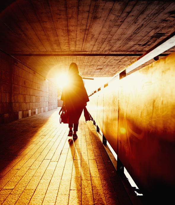 silhouette of a person walking through an illuminated passageway with sunlight filtering in creating a warm glow and shadows highlighting the path to two beautiful moments